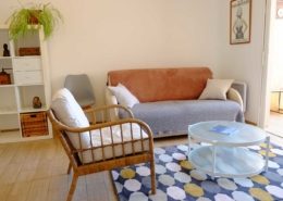 Salon avec canapé et fauteuil en rotin de l'appartement d'hôtes (Saint Mandrier)