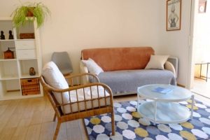 Salon avec canapé et fauteuil en rotin de l'appartement d'hôtes (Saint Mandrier)