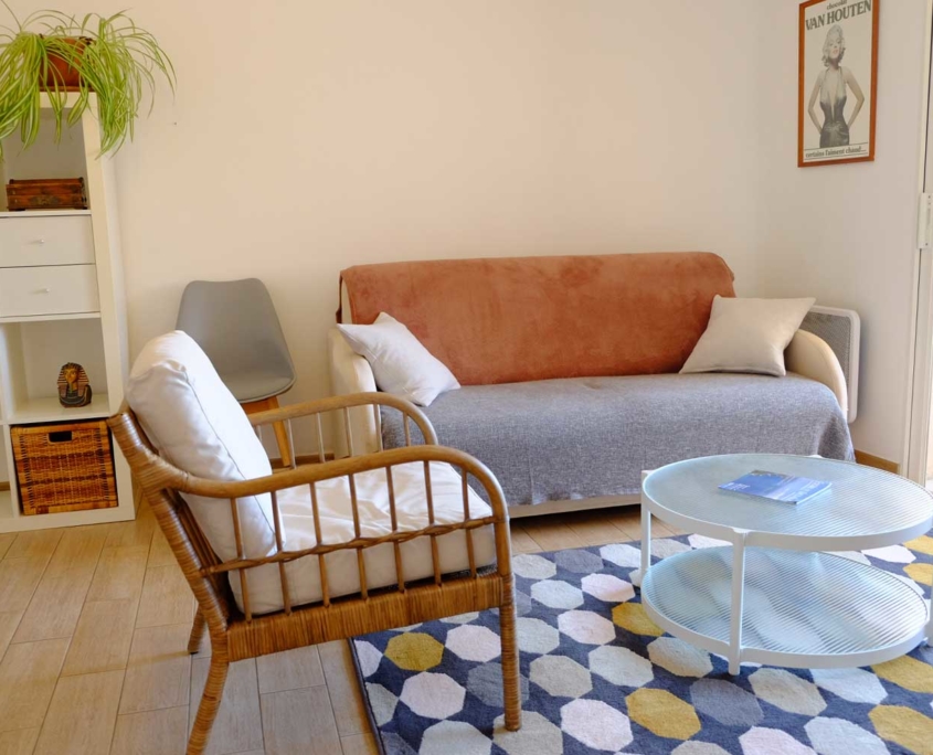 Salon avec canapé et fauteuil en rotin de l'appartement d'hôtes (Saint Mandrier)